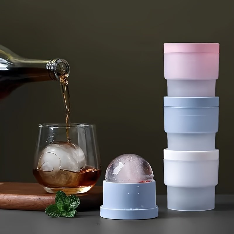 Whisky poured over a large sphere of ice, with three Coldcraft moulds stacked beside the glass